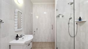 un bagno bianco con doccia e lavandino di H cottages a East London Altre 37 foto