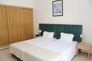a bedroom with two white beds and a green headboard at Hotel Santa Catarina Algarve in Portimão