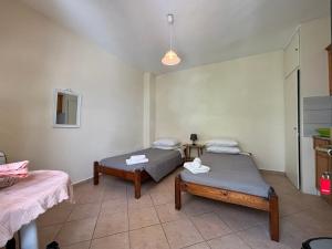 a room with two beds and a table at Antigone's Studio in Kassiopi