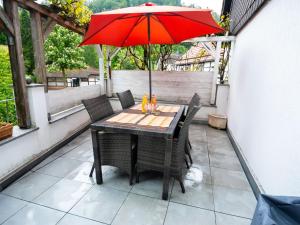 a table and chairs with a red umbrella on a patio at Holiday Home Neles Kate am Diemelsee by Interhome in Helminghausen