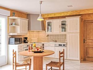 Una cocina con gabinetes blancos y una mesa y sillas. en Holiday Home La Farniente by Interhome, en La Turballe