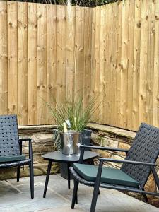 a patio with two chairs and a table and a fence at Cedar Retreat Whitby in Whitby