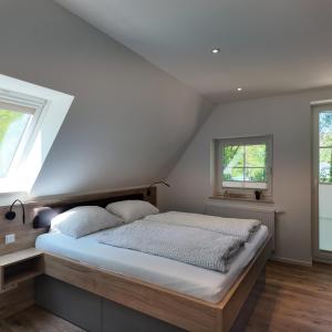 1 Schlafzimmer mit einem Bett mit weißer Bettwäsche und 2 Fenstern in der Unterkunft Klosterhof Aue W 7 in Bad Zwischenahn