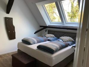 a bed with pillows on it in a room with two windows at Ahrenshof 8 in Bad Zwischenahn