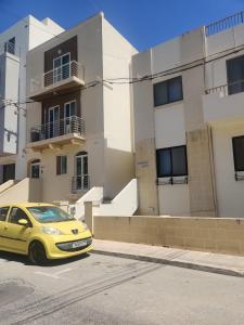 a yellow car parked in front of a building at SeaView Apartment in Taʼ Ġokondu