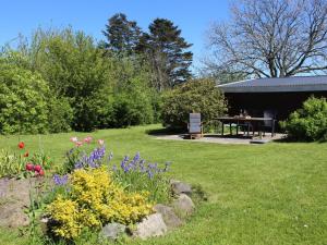 a garden with a table and flowers in the grass at Holiday Home Adrienne - 6-4km from the sea in Bornholm by Interhome in Åkirkeby