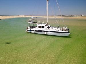 a boat floating in the water near a beach at Barco Casa Fuzeta in Fuzeta