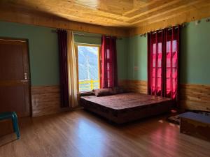 Schlafzimmer mit einem Bett und einem Fenster mit roten Vorhängen in der Unterkunft Valley View Homestay Lahaul in Gondla