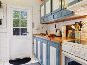 uma cozinha com armários azuis e uma porta branca em Holiday Home Giertrud - 1-1km from the sea in Sealand by Interhome em Vig