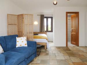 a living room with a blue couch and a bedroom at Apartment Le 55Cici by Interhome in Bouveret