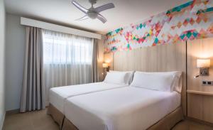 um quarto com uma grande cama branca e uma janela em Allegro Isora em Puerto de Santiago