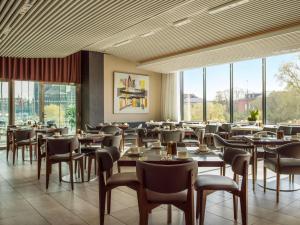 uma sala de jantar com mesas, cadeiras e janelas em Radisson Blu Waterfront Hotel, Stockholm em Estocolmo