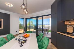 cocina con mesa de comedor y sillas verdes en Apartmani Đogić, en Punat
