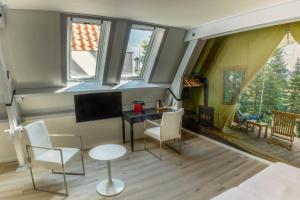 Habitación con mesa, sillas y ventanas. en Hotel de MAGISTRAAT en Willemstad
