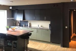 a kitchen with black cabinets and a wooden table at Pen leilighet i Trondheim in Trondheim