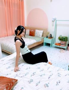 een vrouw zit op een bed bij Wasabi House 2 gần chợ đêm 5p đi bộ in Da Lat