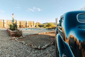 una macchina blu parcheggiata di fronte alla piscina di Windhoek Game Camp a Lafrenz Township