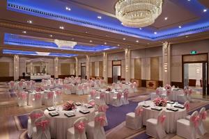 バンガロールにあるITC Gardenia, a Luxury Collection Hotel, Bengaluruの白いテーブルと椅子が備わる大きな宴会場