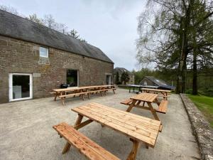 a group of picnic tables in front of a brick building at Moulin du Gast 35pers : jacuzzi sauna billard baby in Le Gast