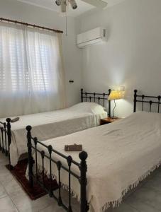 zwei Betten in einem weißen Schlafzimmer mit Fenster in der Unterkunft Pafia A in Paphos City + 11 Fotos