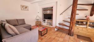 a living room with a couch and a staircase at Maison dans un endroit paisible in Sigonce