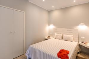 a white bedroom with a bed with a red towel on it at Pedras D'el Rei in Tavira