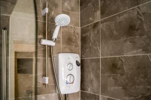 een douche met een douchekop in de badkamer bij K Suites - Station Road in Hinckley