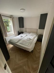 a small bedroom with a bed and a window at Luxe uitgerust vakantiehuis op de Veluwe in Hoenderloo
