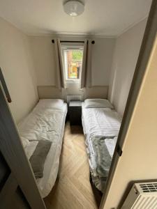 two beds in a small room with a window at Luxe uitgerust vakantiehuis op de Veluwe in Hoenderloo