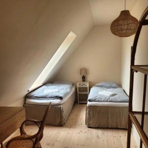 un dormitorio en el ático con 2 camas y una silla en Atma Guesthouse - cozy and simple bed & breakfast in the countryside, en Marstal