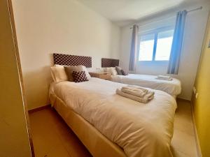 a room with two beds with towels on them at Condado de Alhama, NARANJOS 4 SV08 in El Romero