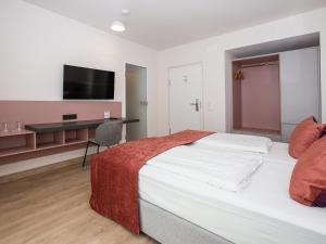 a bedroom with a bed and a desk with a television at Hotel Bargenturm in Lüneburg