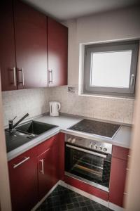 a kitchen with red cabinets and a sink and a window at Ferienwohnung-Bali in Bad Liebenzell