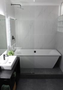 a white bathroom with a tub and a sink at The Wild Suite in Wilderness