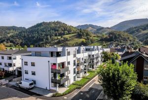 eine Luftansicht auf ein weißes Apartmenthaus mit Bergen im Hintergrund in der Unterkunft Ferienwohnung Sternenblick in Schönau im Schwarzwald