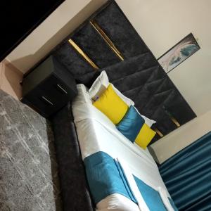 a bedroom with a bed with blue and yellow pillows at Exquisite 2BR Ensuite Apartment close to Rupa Mall, Mediheal Hospital, and St Lukes Hospital in Eldoret