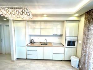 una cucina con armadi bianchi, lavandino e lampadario pendente di Blue Marlin Apartments a Budua