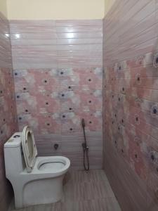 a bathroom with a white toilet and pink tiles at Anant Paying Guest house in Ayodhya