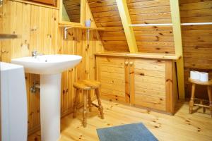 uma casa de banho com um lavatório num quarto de madeira em The Rainbow - Domki Letniskowe em Dźwirzyno