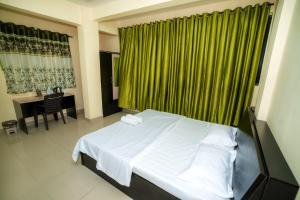 1 dormitorio con cama blanca y cortina verde en Paradise Homestay, en Pune