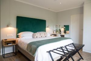 a bedroom with a large bed with a green headboard at Penguino Guesthouse in Hermanus