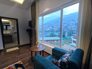 un soggiorno con divano blu e una grande finestra di Asura hotel a Thimphu Altre 3 foto