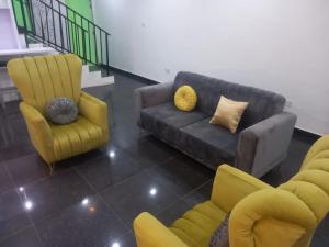 Mega Pavilion Apartment And Suits Gwarinpa في Gwarinpa: غرفة معيشة مع أريكة وكرسيين