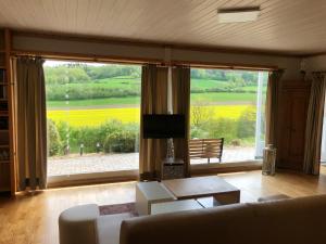 un salon avec un canapé et une grande fenêtre dans l'établissement Idyllisch Wohnen im Weserbergland - Bungalow mit phantastischer Aussicht für 4 Personen, à Polle