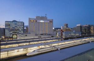 ein Zug auf einem Gleis in einer Stadt mit Gebäuden in der Unterkunft Hotel Associa Shizuoka in Shizuoka