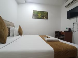 a bedroom with a large white bed and a desk at Hotel Prime Royalty Malviya Nagar in New Delhi