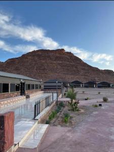 a building with a mountain in the background at Bedouin desert life camp& Jeep tours in Wadi Rum