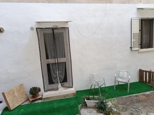 ein weißes Haus mit einem Stuhl und einem Fenster in der Unterkunft Dimora San Giorgio con parcheggio auto privato in Gravina in Puglia