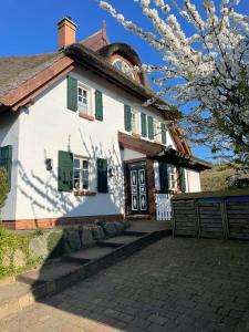 a large white house with green shutters at Insel Landhaus Feuerstein in Gager