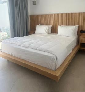 1 cama grande con sábanas y almohadas blancas en Mykonos Drops, en Platis Gialos